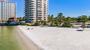 Ein Hotel direkt am Strand mit mehreren Etagen, einem Sandstrand und Palmen.