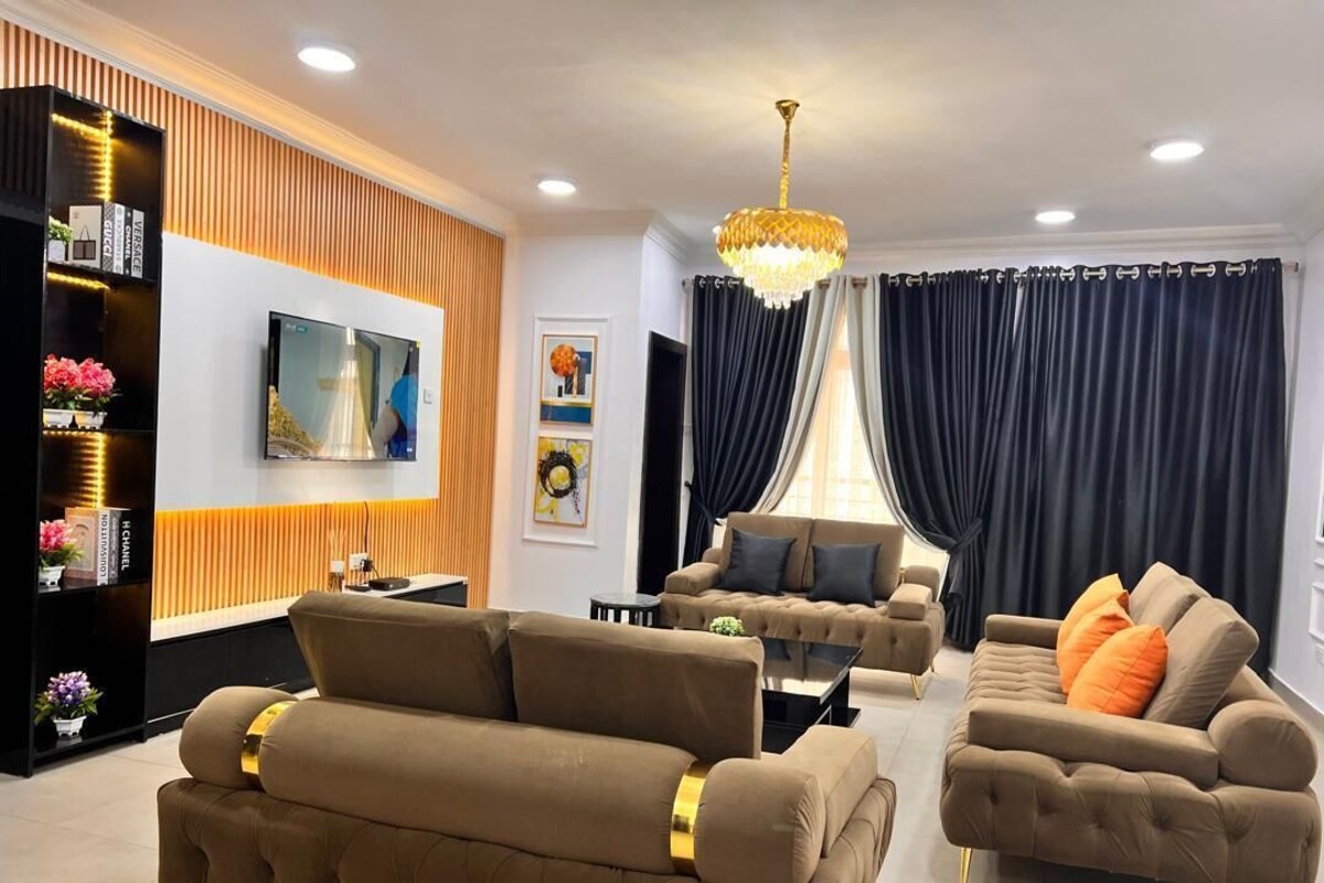 A modern living room with two sofas, a TV, and a chandelier.