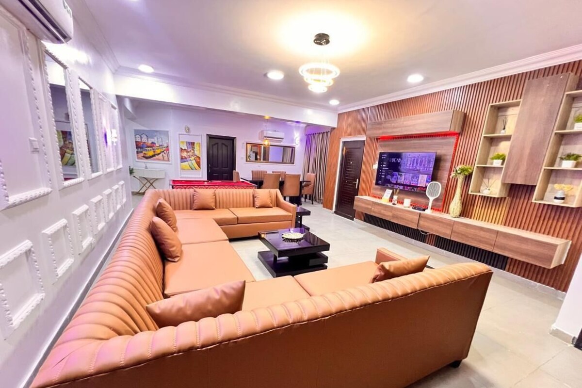 A modern living room with a large sectional sofa, a flat-screen TV, and a wooden accent wall.