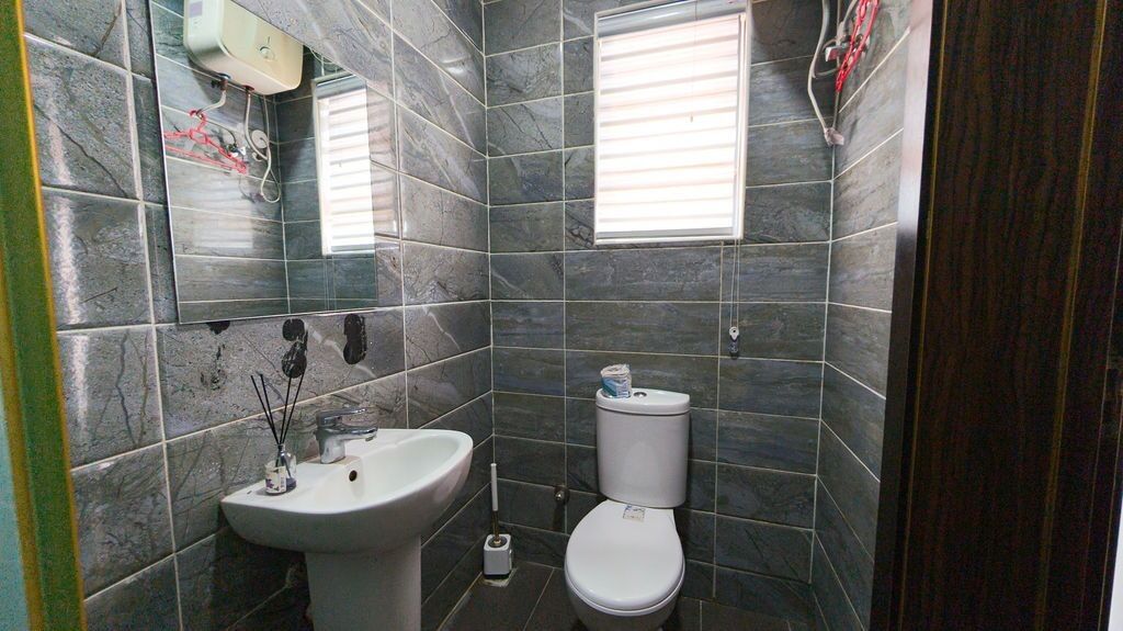 A bathroom with a sink, toilet, and a window.