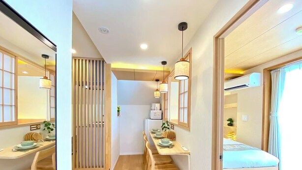 A modern hotel room with a wooden dining table, a sofa, and a kitchen area with a refrigerator and microwave. - H401 ＊[New] Tokyo luxury guesthouse｜Japanese style 2DK｜Honjo-Azumabashi station & direct airport access｜Near Asakusa & Skytree (墨田 区)