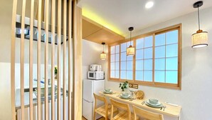 A compact kitchen with a dining area, featuring a wooden table, chairs, a refrigerator, and a window with a grid pattern. - H401 ＊[New] Tokyo luxury guesthouse｜Japanese style 2DK｜Honjo-Azumabashi station & direct airport access｜Near Asakusa & Skytree (墨田区)