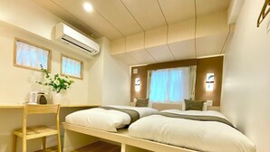Ett modernt hotellrum med en säng, sängbord, ett skrivbord och en luftkonditioneringsanläggning.
