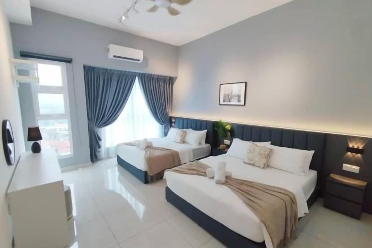 Habitación de hotel con dos camas, un escritorio y vistas al exterior.