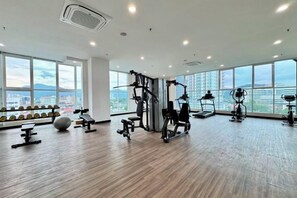 Een sportschool met trainingsapparatuur, grote ramen en uitzicht over de stad.