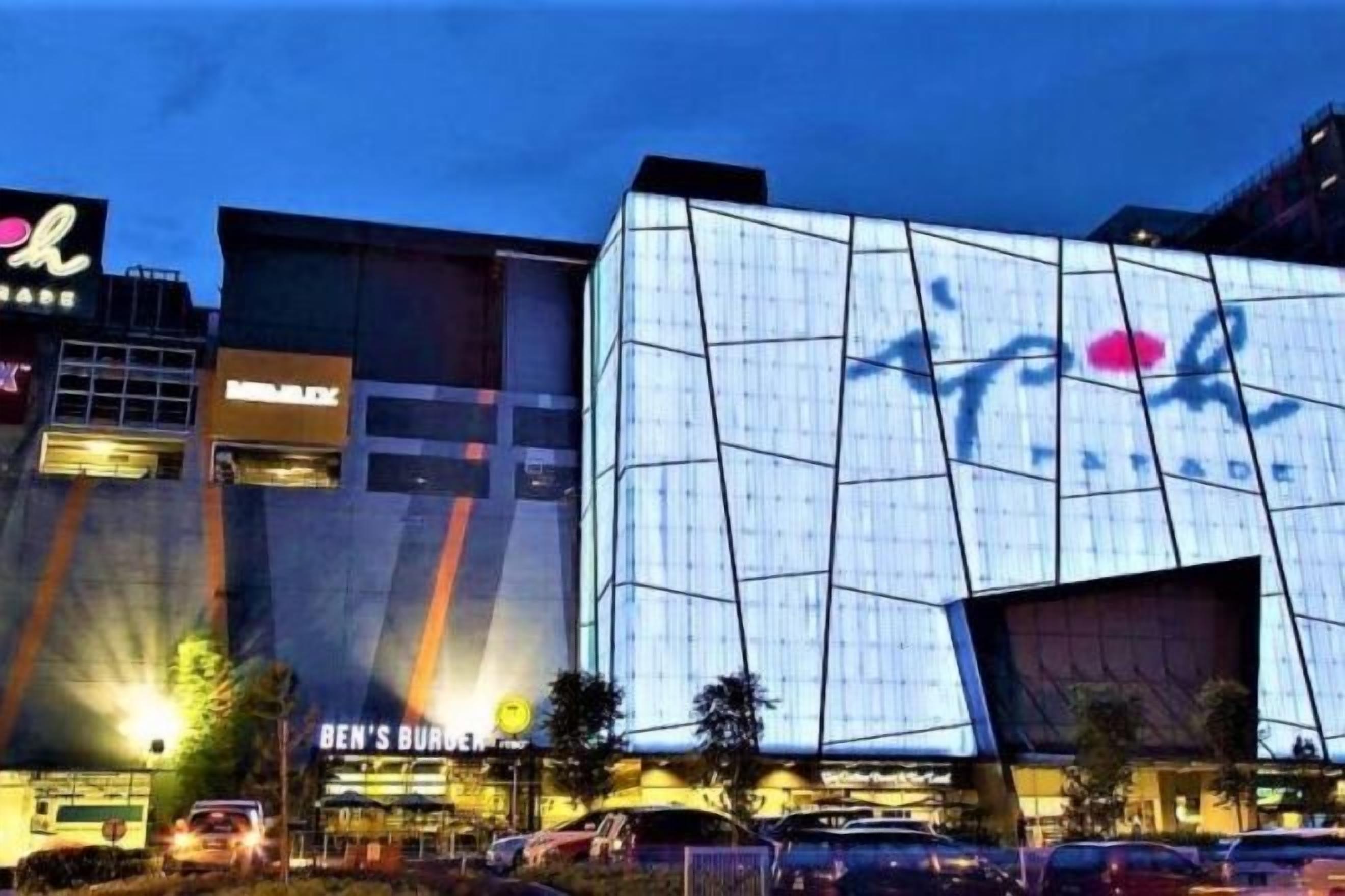 Un edificio moderno con fachada geométrica, un logotipo destacado y un restaurante Ben's Burger cercano.