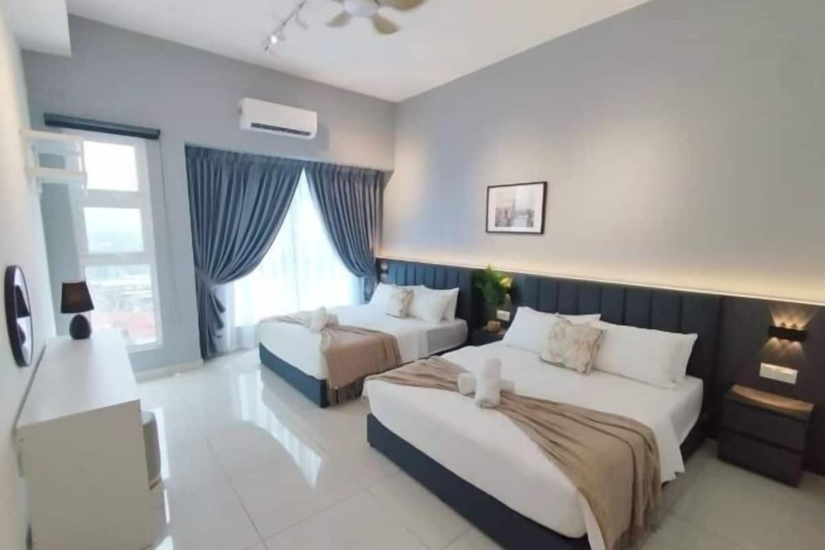 Habitación de hotel con dos camas, un escritorio, una silla, un ventanal con cortinas, un equipo de aire acondicionado y un cuadro en la pared.