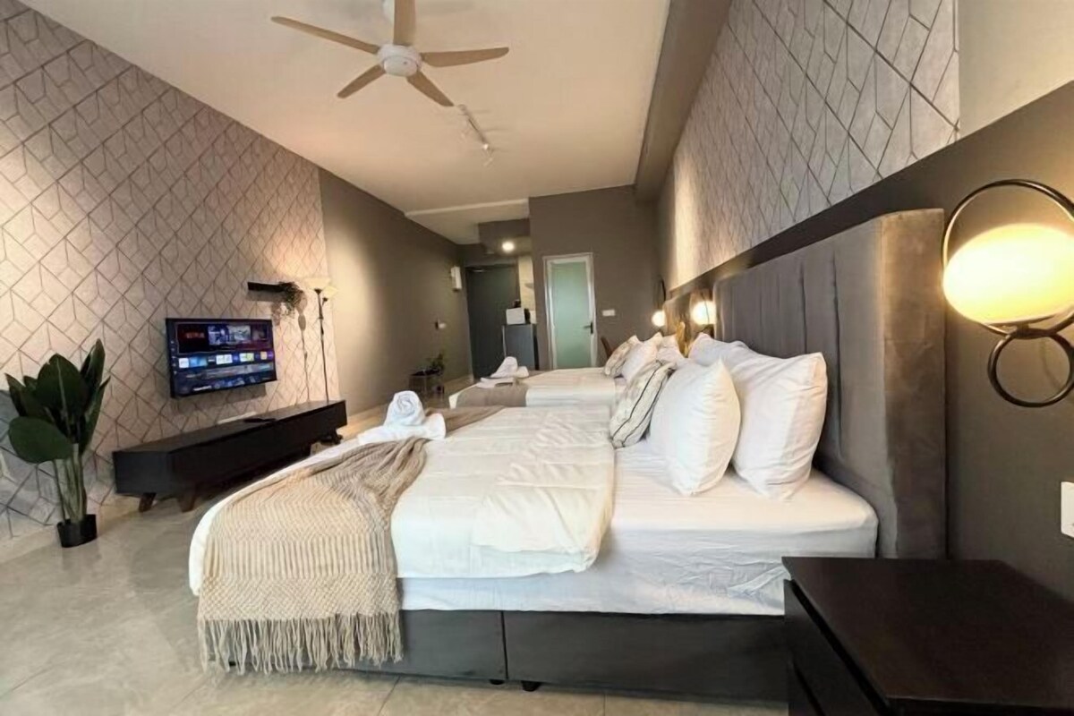 Une chambre d’hôtel équipée d’un lit, d’une télévision, d’un ventilateur de plafond et d’un luminaire fixé au mur.
