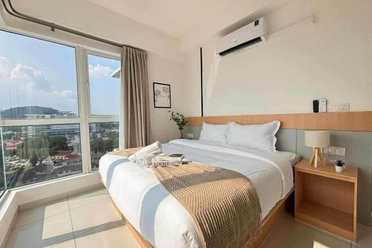 Habitación de hotel con una cama grande, una mesita de noche y un equipo de aire acondicionado. Cuenta con una ventana con vistas.