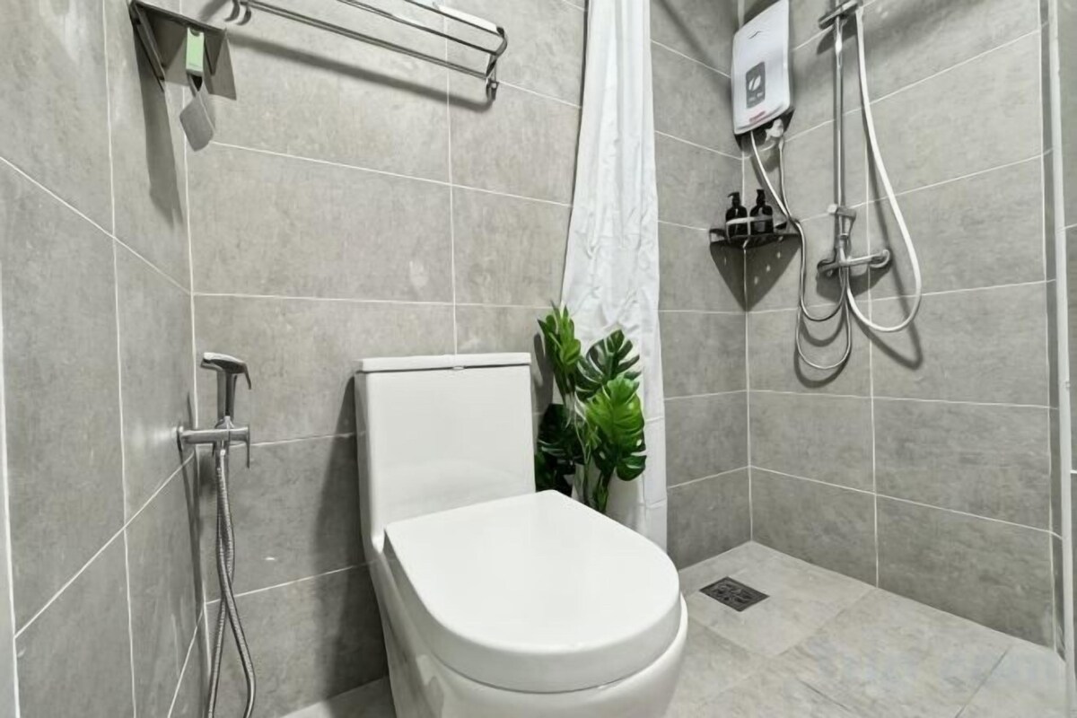 A modern bathroom with a toilet, shower, and a plant.