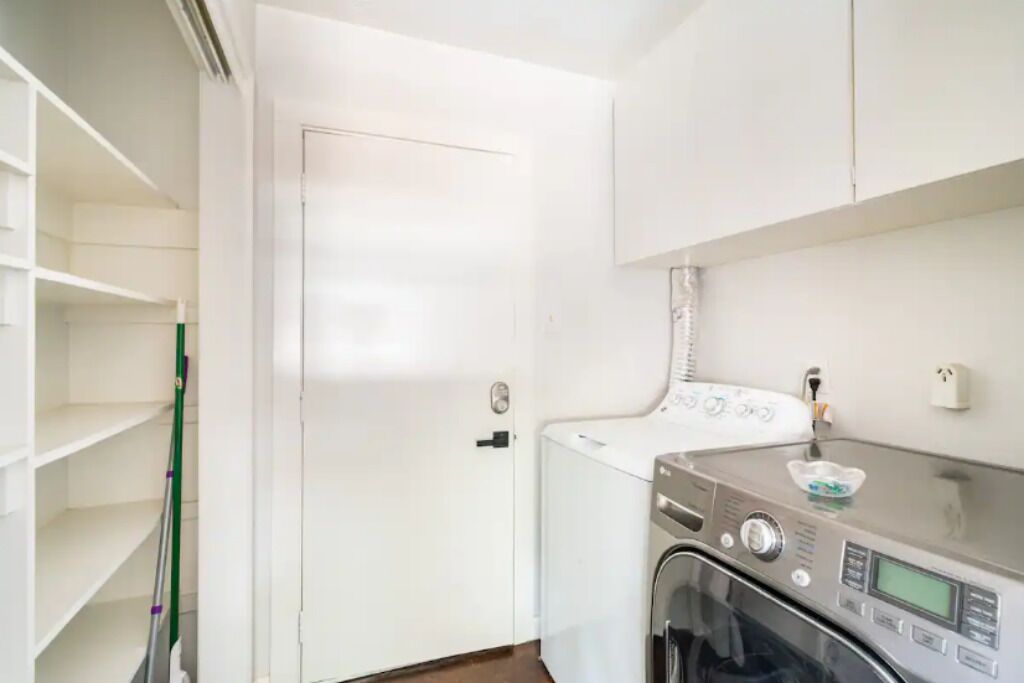 A laundry room with a washing machine, a drying machine, and a mop leaning against the wall.