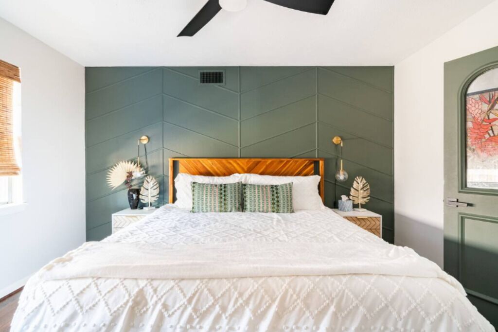 Een slaapkamer met een bed, nachtkastjes en een groene accentmuur.