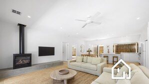Ein geräumiges Wohnzimmer mit Kamin, einer Couch, einem Couchtisch und einem Essbereich.