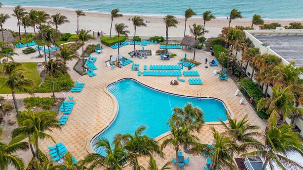Un complexe hôtelier doté d’une grande piscine, de chaises longues et de palmiers.