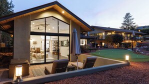 A modern house with a large glass door leading to a living area, outdoor seating, and a well-lit patio. - Sedona At the Wild Horse, Wellness Retreat, Gameroom, Cold Plunge, West & Dry Sauna (Sedona)