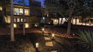 A modern house with a stone facade, a visible staircase, and a well-lit garden area with trees and a pathway. - Sedona At the Wild Horse, Wellness Retreat, Gameroom, Cold Plunge, West & Dry Sauna (Sedona)