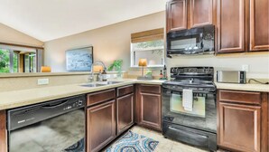 A modern kitchen with dark wood cabinets, a stainless steel stove, and a dishwasher.