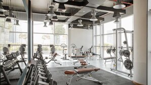 Een sportschool met diverse fitnessapparaten, grote ramen en een hoge nok.