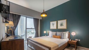 Een moderne slaapkamer met een groot bed, nachtkastjes, een bureau en uitzicht op de stad.