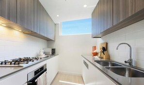 Una cocina moderna con estufa a gas, microondas y pileta de acero inoxidable.