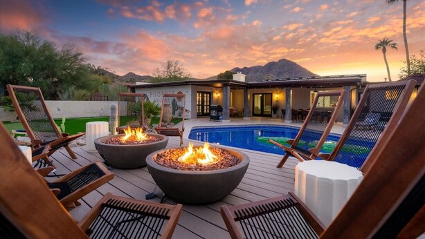 A poolside area with lounge chairs, a fire pit, and a view of a mountain at sunset. - Mini Resort w/ Mountain Backdrop | Heated Pool, Hot Tub, Sauna, Cold Plunge (Phoenix)