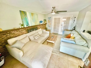 A living room with a beige sectional sofa, a blue sofa, a wooden coffee table, and a ceiling fan. - 3-bedroom house in peaceful Central Phoenix with Pool  GCU, Uptown, and DT (Phoenix)