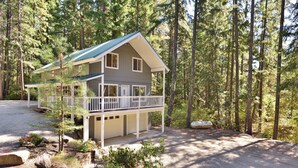 Eine zweistöckige Hütte mit Balkon, umgeben von einem Wald.