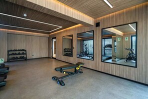 A gym with exercise equipment, mirrors, and wooden paneling.
