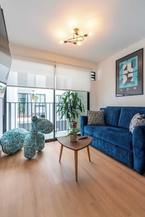Ein modernes Wohnzimmer mit einem blauen Sofa, einem Couchtisch und Sitzsäcken mit Muster.