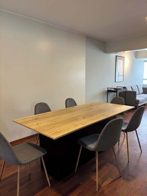 Ein stilvoller Essbereich mit Holztisch und vier Stühlen, einer Couch und einem gerahmten Bild an der Wand.