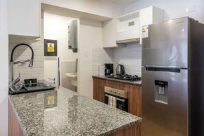 Eine Küche mit Granitarbeitsplatten, einem Edelstahlkühlschrank, einem Herd und einem Spülbecken.