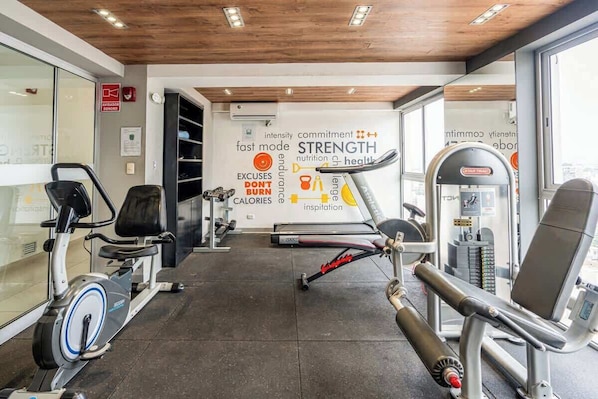 A gym with exercise equipment, a wall with motivational words, and a window. - Geko | Functional Loft next to Malecón w/Pool (Barranco)