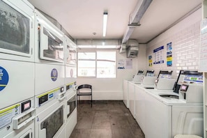 A laundry facility with multiple washing machines, a chair, and instructional posters on the walls. - Geko | Functional Loft next to Malecón w/Pool (Barranco)