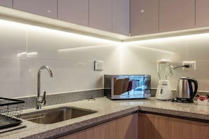 A modern kitchen with a built-in microwave, a coffee maker, and a kettle on the counter. - Geko | Spectacular 2BR near Malecon w/ balcony (Miraflores)