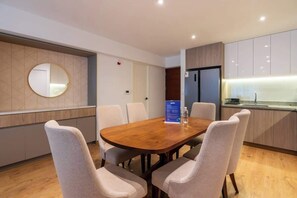 A modern kitchen with a wooden table and chairs, a round mirror, and a refrigerator. - Geko | Spectacular 2BR near Malecon w/ balcony (Miraflores)