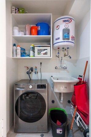 Ein kleiner Hauswirtschaftsraum mit Waschmaschine, Spüle und Warmwasserbereiter.