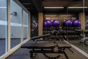 Ein Fitnessraum mit Trainingsgeräten, einer Bank und einer Wand mit motivierenden Texten.