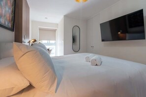 Ein Hotelzimmer mit einem Bett, Kissen, einem Fernseher, einem Spiegel und einem Fenster.