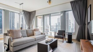 A modern living room with a grey sofa, a coffee table, and a chair. Large windows offer a view of the cityscape. - Blueground | Burj Residence Phase I & II, pool, nr Burj Khalifa (Dubai)