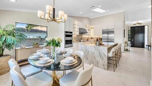 Una cocina moderna con armarios blancos, una isla de mármol y electrodomésticos de acero inoxidable.
