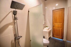 Un baño con ducha, inodoro y puerta de madera.