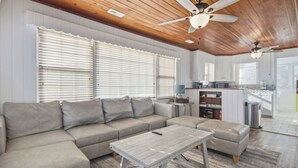 A modern living room with a sectional sofa, a coffee table, and a ceiling fan. - Walk to the Ocean • Beach Access • Furnished Deck (North Myrtle Beach)