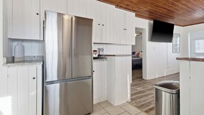 A modern kitchen with white cabinetry, stainless steel appliances, and a wooden ceiling. - Walk to the Ocean • Beach Access • Furnished Deck (North Myrtle Beach)
