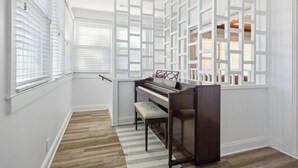 A piano in a corner of a room with white walls and wooden flooring. - Walk to the Ocean • Beach Access • Furnished Deck (North Myrtle Beach)