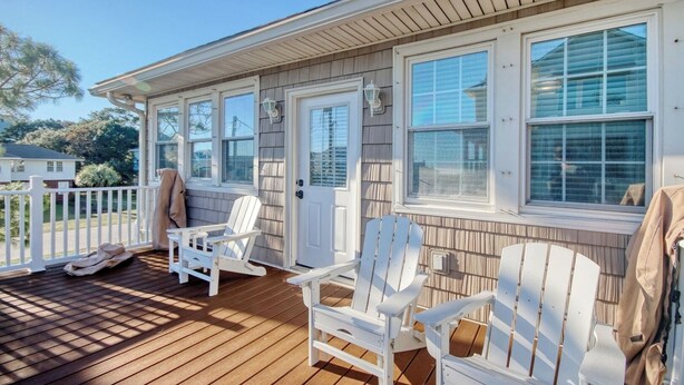 A covered porch with white Adirondack chairs, a wooden deck, and a white door with a window. - Walk to the Ocean • Beach Access • Furnished Deck (North Myrtle Beach)