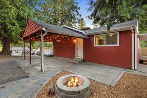 A red house with a fire pit in the yard, a covered porch, and a garage. - Quaint 2-bedroom cottage in Seattle (Seattle)