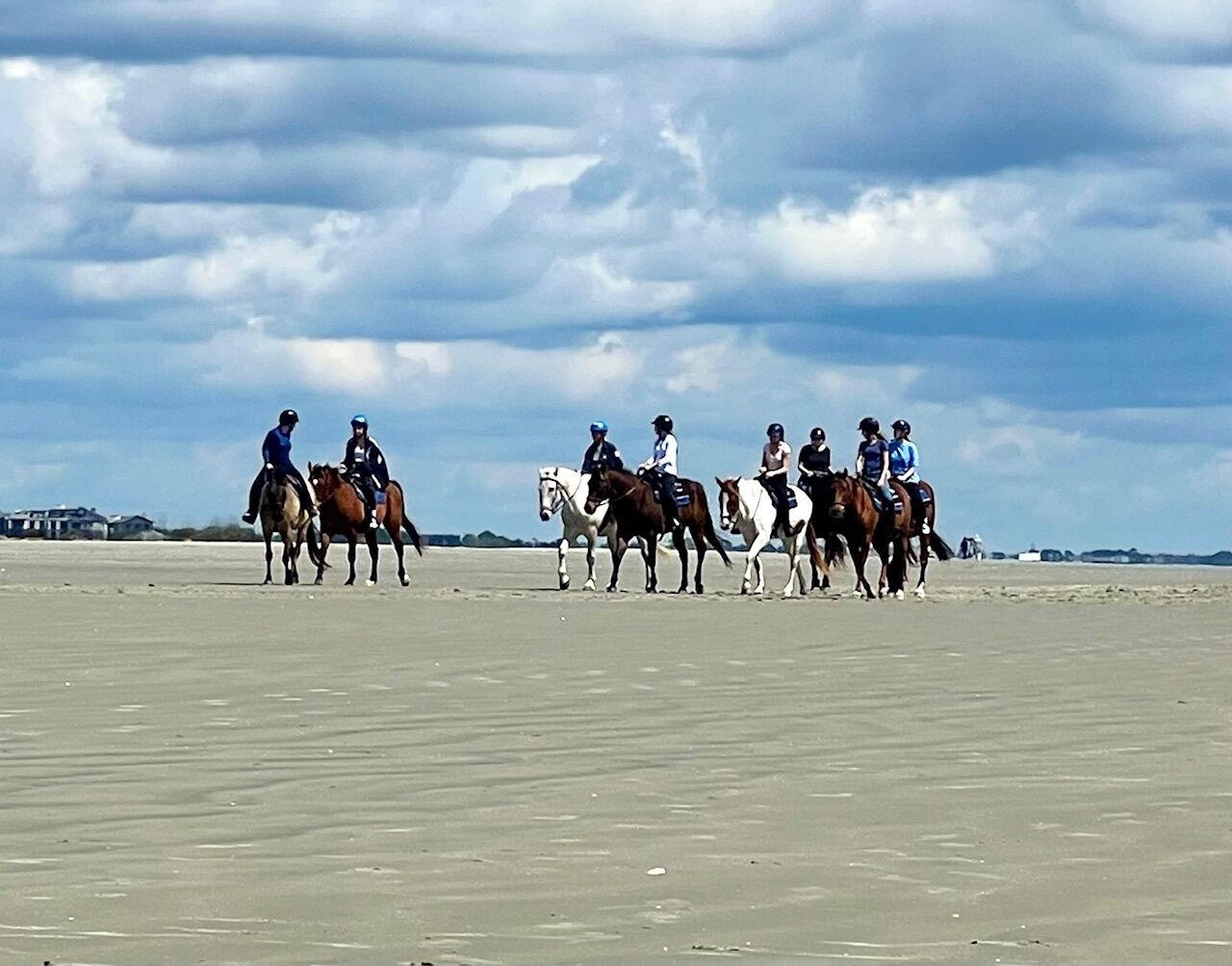 Una playa con gente montando a caballo.