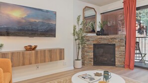 Ein Wohnzimmer mit Kamin, einem Wandfernseher und einem großen Gemälde.