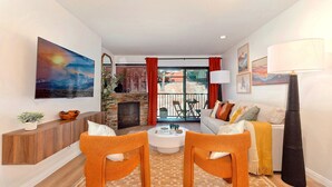 Ein Wohnzimmer mit Kamin, orangefarbenen Sesseln, einem weißen Sofa und einem großen Gemälde an der Wand.