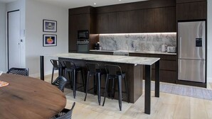 Een moderne keuken met donkerhouten kastjes, een marmeren achterwand en roestvrijstalen apparatuur.